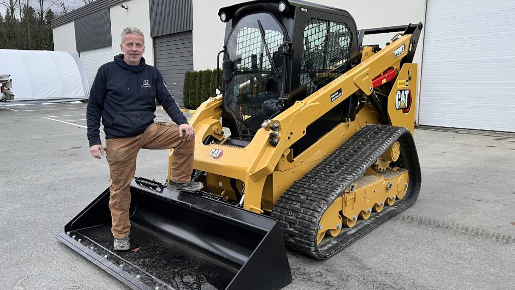 Bjorn Grimsmo owner of VIP Landscaping standing beside CAT mini excavator used for excavation services in Langley and the Fraser Valley